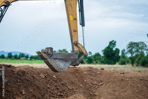Fototapeta A mini excavator is digging the soil in the field.