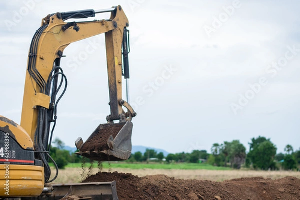 Fototapeta mini excavator digging soil with mountain background