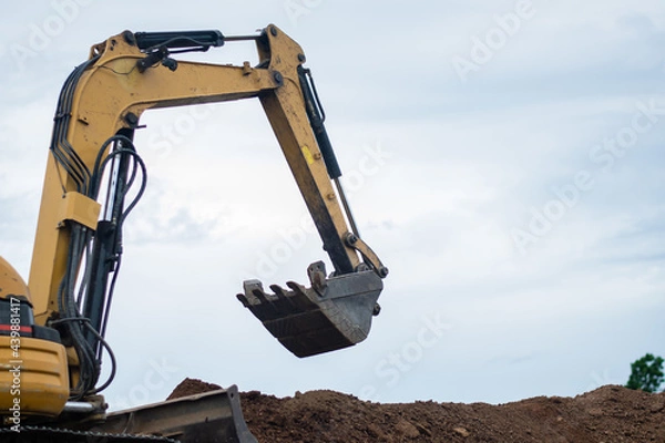 Fototapeta A mini excavator is digging the soil in the field.