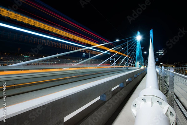 Fototapeta Light trails from a passing train at night on Tilikum Crossing Bridge in Portland, Oregon