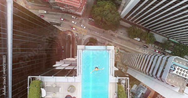 Fototapeta AERIAL. Top view of Hong Kong streets from the drone. And woman at the sweeming pool.