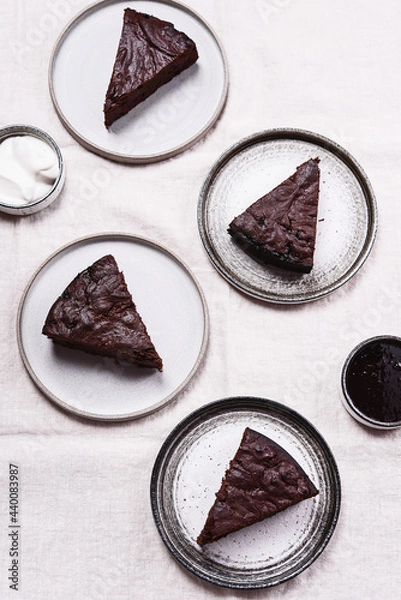 Fototapeta Slices of rich moist chocolate cherry cake. Homemade dark chocolate sweet brownies cakes with ice cream on greige linen tablecloth. Selective focus