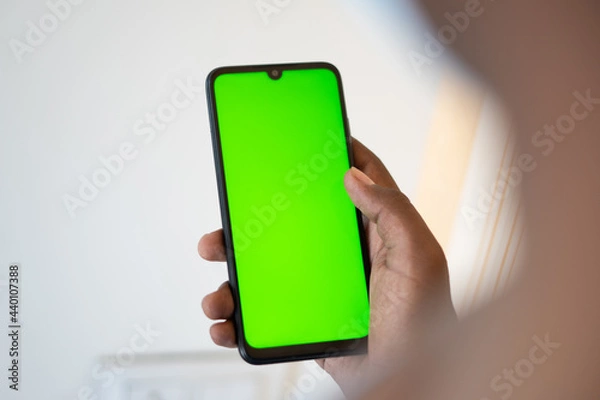 Fototapeta Closeup shot of hand using mobile phone with Green screen, Finger swiping up and down in green screen of the mobile. Green screen mockup template of Mobile phone, Chroma key	