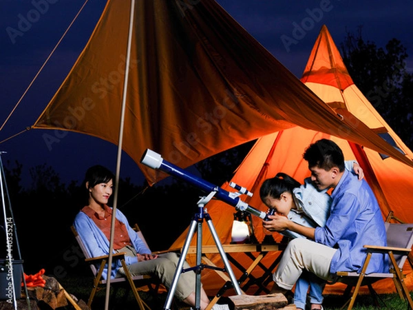 Obraz A happy family of three using telescopes outdoors