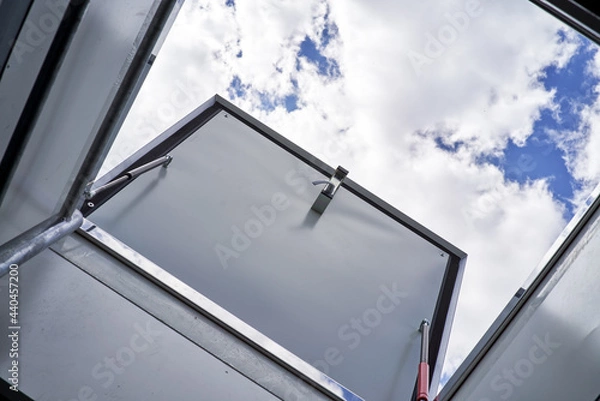 Fototapeta open hatch for roof access cloudy sky on background