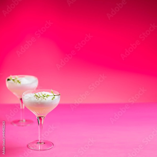 Fototapeta White gin cocktail with egg foam garnished with white flowers on pink background. Copy space.