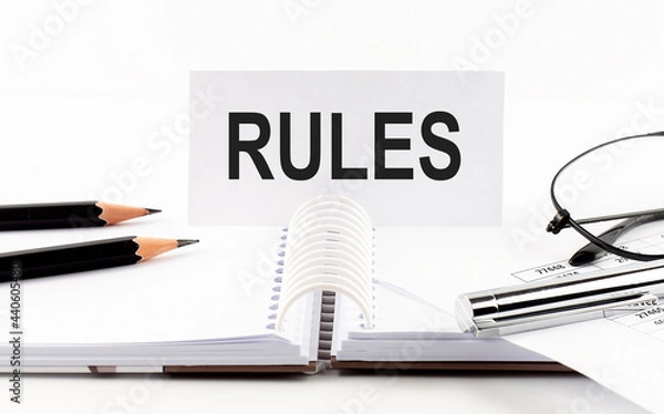 Fototapeta RULES on paper card,pen, pencils, glasses,financial documentation on table - business concept