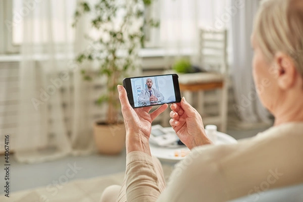 Fototapeta Sick woman during a video call with a doctor. Side view of patient talking during conference call with his doctor while at home
