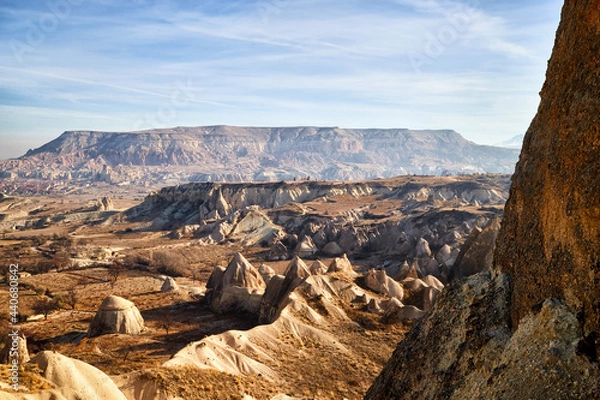 Fototapeta View from top place on the strange landscape in the Cappadocia valley with yellow mountains, rocks and hills and blue sky with white clouds