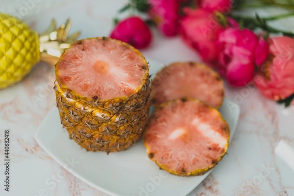 Obraz sliced pink pineapple on plate with pink flowers