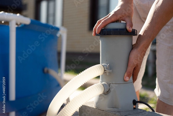 Fototapeta A man checks a filter for cleaning a home pool. Keeping the swimming pool clean