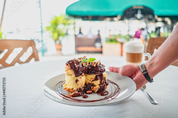 Obraz profiterole dessert served with chocolate and a cappuccino 