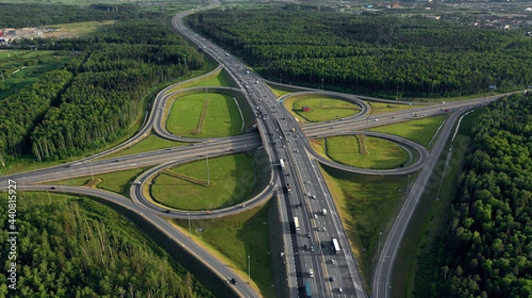 Fototapeta AERIAL. Traffic interchange. Top view of the road, city and forest. Summer video from the drone.