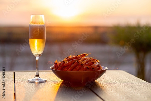 Fototapeta Shrimps with beer at sunset near the sea. Summer. Shrimp with champagne at sunset Summer concept. Seafood with beer. Sea sunset with champagne. Beautiful sunset. Cold beer with shrimps. King prawns 