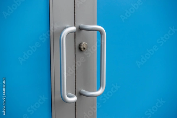 Fototapeta silver door handles outside of a business building, with a blue screen effect