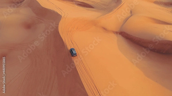 Fototapeta AERIAL. Hight flight above car. Desert safari car sand dunning in the Dubai desert during sunset
