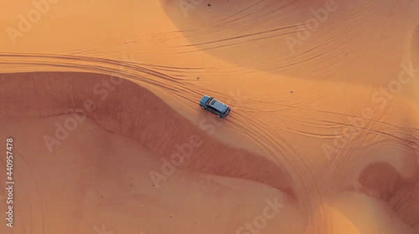 Fototapeta AERIAL. Hight flight above car. Desert safari car sand dunning in the Dubai desert during sunset
