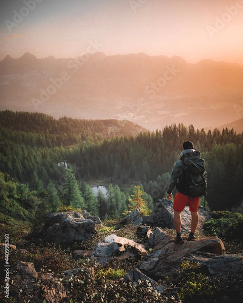 Fototapeta Hiker with Backpack standing on Mountain Peak - Enjoying View in the austrian alps near Schladming