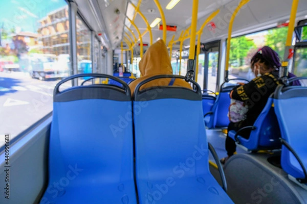 Fototapeta Defocused people on the bus. Empty blue seats in a bus close-up. Public urban transportation	
