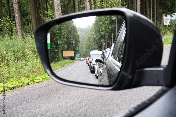 Fototapeta Car side mirror with traffic jam on a road in a forest