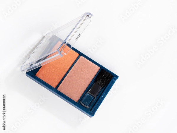 Obraz A box with blush on a white background. Blue plastic blush pack with a transparent lid and a small brush. Red and beige blush. decorative cosmetics. Compact blush for the face. Cosmetics for women.