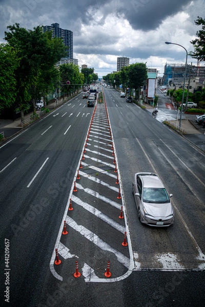 Fototapeta 縞模様の白線が劣化して剥がれていて車が走っているアスファルト道路