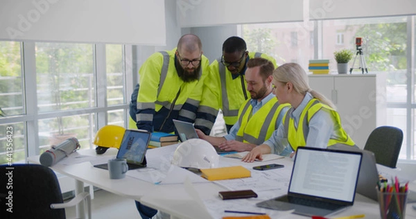 Fototapeta Professional diverse engineers discussing new project using laptop in office
