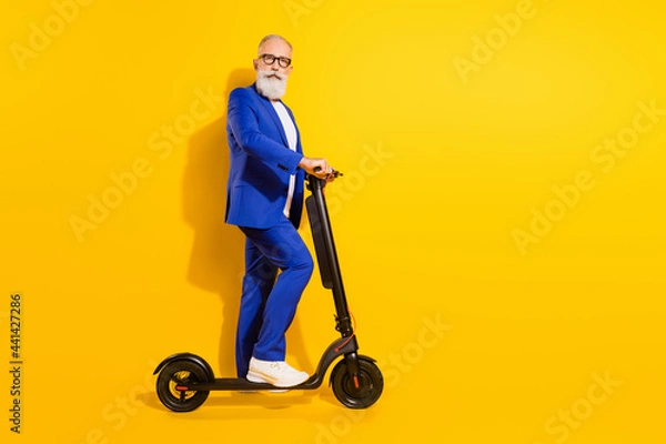 Fototapeta Full length body size profile side view of elegant funky man riding eco kick scooter isolated over bright yellow color background
