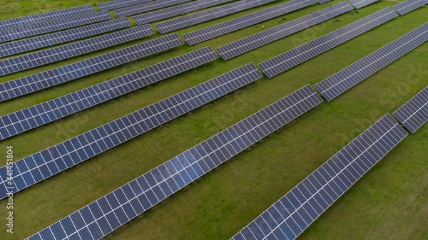 Fototapeta Aerial view of Solar Panels Farm solar cell with sunlight. Drone flight over solar panels field, renewable green alternative energy concept.