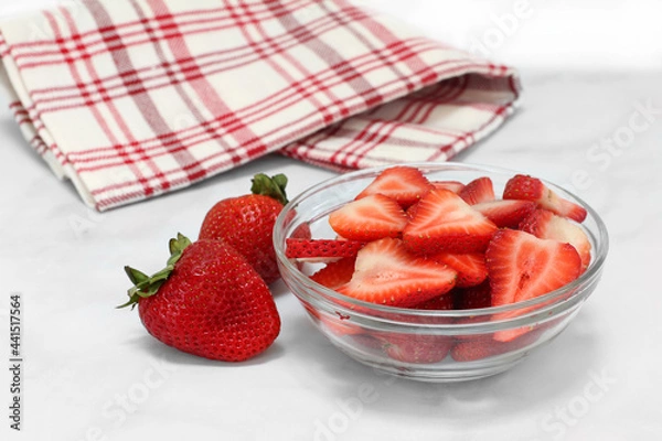 Obraz A glass bowl of sweet sliced strawberries with whole berries to the side.