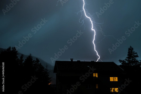 Obraz Blitze über einem Haus zwischen Bäumen