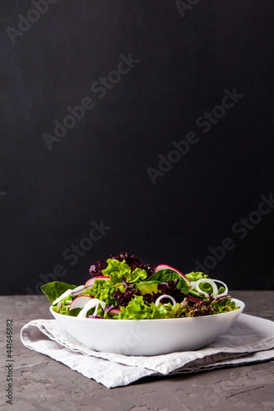 Fototapeta Healthy salad, leaves mix salad in a bowl over dark background. Copy space.