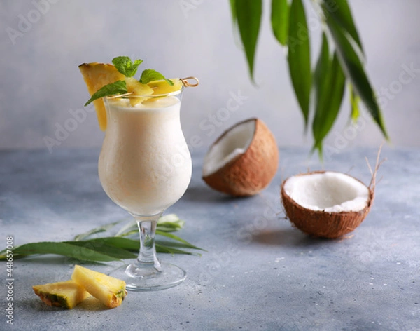 Fototapeta Summer. Drinks and cocktails. Pina colada in glass with pineapple, coconut, mint and a branch of greenery on a light gray background. Background image, copy space