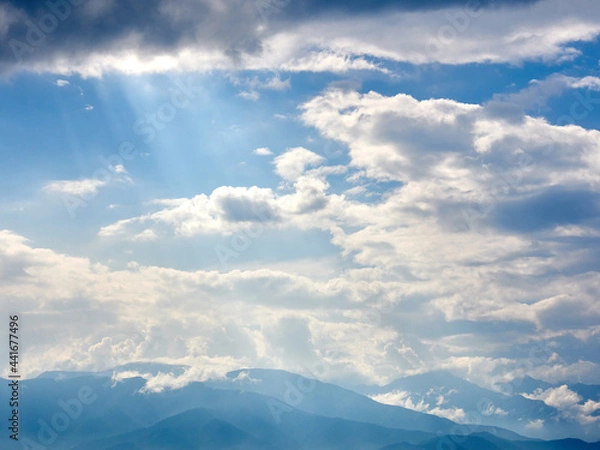Obraz 6月下旬、雲間から差し込む光芒と山並みの風景