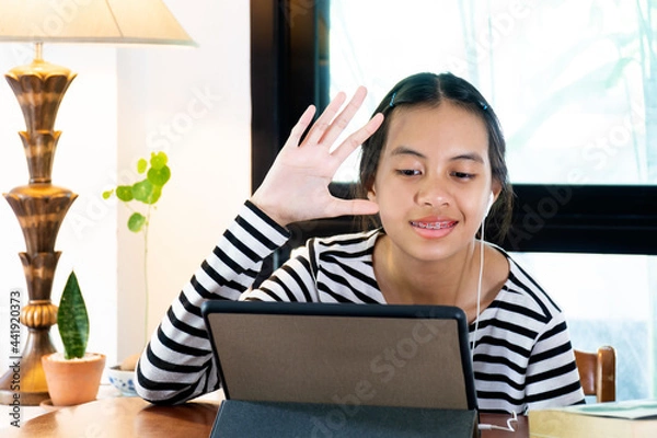 Obraz Girl wearing head set and studying online at home during home quarantine.