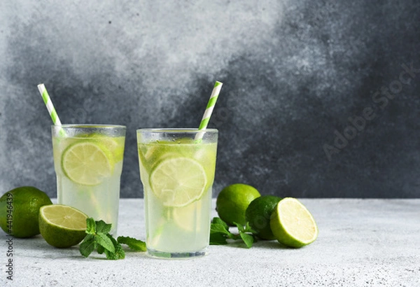 Fototapeta Iced tea with lime. Cold lemonade with lime on a concrete background.