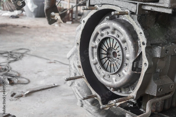 Fototapeta Mechanic repairing disassembled engine. Old tractor  is working with a tractor engine in a garage