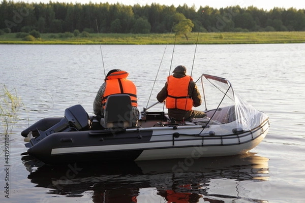 Fototapeta Two fishers in orange lifejackets floats on modern inflatable motor boat with 9.9 hp outboard motor that does not require registration, recreation with fishing rods on the Russian river at summer day
