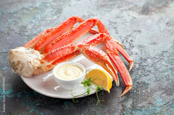 Obraz Crab legs with sauce and lemon on a plate, selective focus