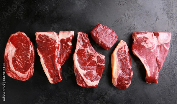 Fototapeta Assorted raw meat steaks. Japanese marble wagyu meat on a black table. Background image, copy space. Top view, flatlay