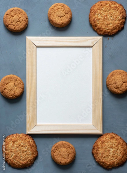 Obraz Stationery mock-up scene dedicated to healthy eating. Blank white greeting card in wooden frame surrounded by fresh oatmeal cookies on textured gray background.