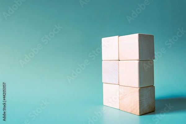 Obraz A stack of six wooden cubes on a light blue background. Mockup, copy space. Concept business picture.
