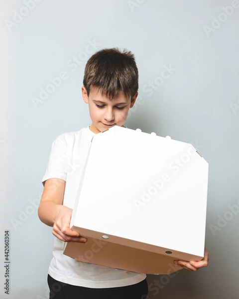 Fototapeta Small boy opening white pizza box over white background. Copy space banner. Junk food, fast food concept.