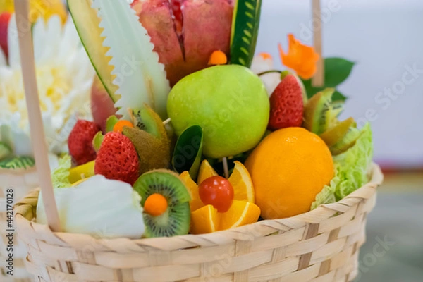 Fototapeta Colorful fruits bouquet in wicker basket on table - close up view