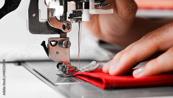 Obraz Woman's hands with red fabrics at sewing machine. Self made clothes concept.Hobby concept. Clothes repairing concept.