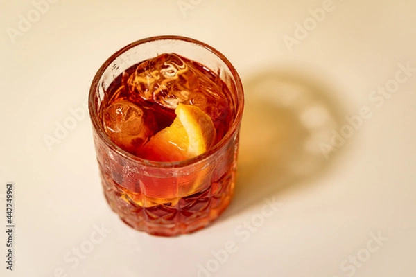Fototapeta Top view of Negroni cocktail with orange wedge on white surface