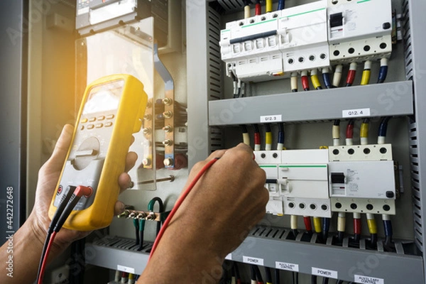 Fototapeta An electrician work tester measuring the voltage and current of electric power line in an electrical cabinet control.