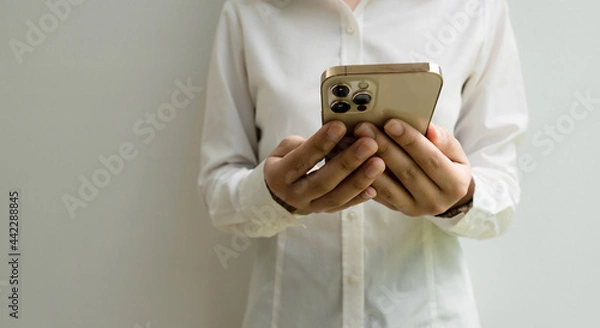 Fototapeta Close up of woman using mobile smart phone on a gray background