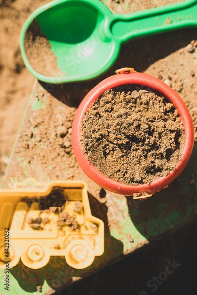 Fototapeta Bucket With Sand, Shovel And Form On Sandpit In Spring Top View.