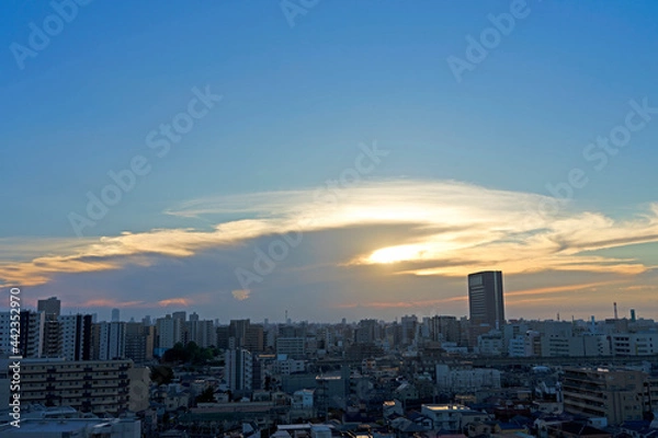 Fototapeta 雲間から見える夕日と街